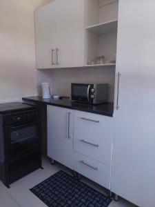 a kitchen with white cabinets and a black stove at Diamonds on 2 Patricia Place in King Williamʼs Town