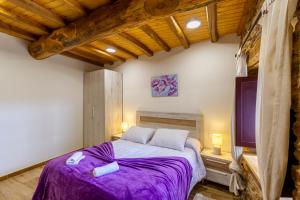 sypialnia z dużym łóżkiem z fioletową pościelą w obiekcie Casa Añolo w mieście Sober