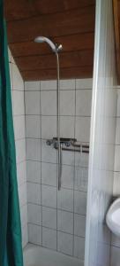 eine Dusche im Bad mit einer weiß gefliesten Wand in der Unterkunft Balatonmáriafürdő Szabó apartman in Balatonmáriafürdő