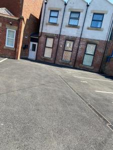 an empty parking lot in front of a brick building at Manchester Apartment with Free Gated Parking by Daley Stays in Manchester