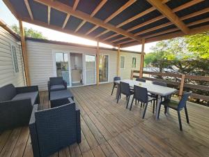 una terraza de madera con mesa y sillas. en Camping Le Dolium, en Laudun