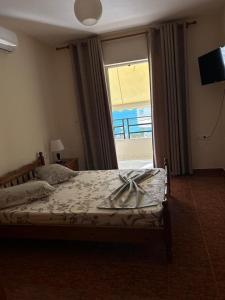 een slaapkamer met een bed en een groot raam bij Relax Apartment in Sarandë
