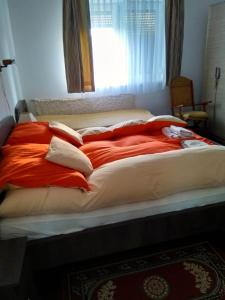 a large bed with red and white blankets and pillows at Kökörcsin Vendégház in Tornaszentandrás