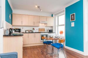 a kitchen with a table and chairs and a blue wall at Seaview Oasis - Margate Abode - Sleeps 4 in Kent