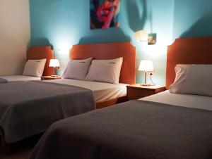 a hotel room with two beds and two lamps at Plakoudis Rooms in Stavros