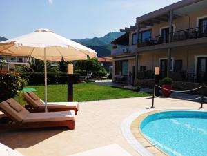 a patio with an umbrella and chairs and a pool at Plakoudis Rooms in Stavros