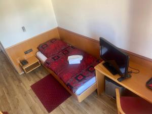 a small room with a bed and a desk with a computer at City Pension in Rastatt