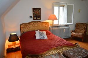 una camera con un letto con un piumone rosso e una sedia di Chez Thérèse et Marguerite 