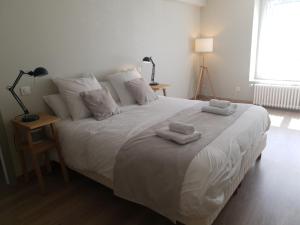 um quarto com uma grande cama branca com toalhas em Maison de ville située à 8 kms du Mont St Michel em Pontorson