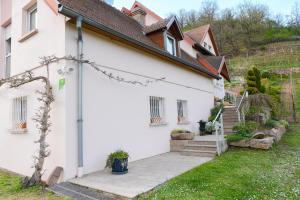a white house with a stairway leading up to it at Les Glycines du Sommerberg in Niedermorschwihr