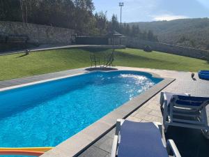 a swimming pool with two chairs next to a yard at Refúgio in Castelo de Paiva