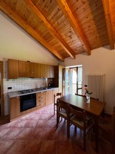 a kitchen with a wooden table and a wooden ceiling at Appartamenti Casa Miravalle in Enguiso
