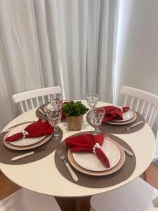 uma mesa branca com guardanapos vermelhos e pratos em Apto ao lado do Shopping Caruaru próximo ao pátio unidade 302 em Caruaru