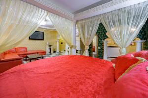 a bedroom with a large red bed with white curtains at Gostiniy Dvor in Odesa +65 photos
