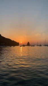 un coucher de soleil sur une étendue d'eau avec des bateaux dans l'établissement Casa Vacanze Residence Baia Fenicia Vulcano, Isole Eolie, à La Fabbrica