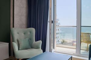 a living room with a chair and a large window at Vogue Sunrise View in Infinity Pool & Spa Resort in Mamaia Sat/Năvodari