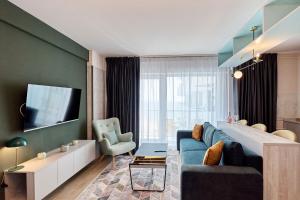 a living room with a blue couch and a tv at Vogue Sunrise View in Infinity Pool & Spa Resort in Mamaia Sat/Năvodari