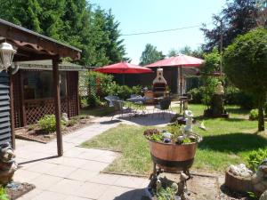 a garden with a table and chairs and red umbrellas at Ferienhaus Tanneneck in Pottum