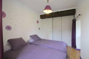 een slaapkamer met een bed met paarse lakens en een lamp bij Gite TY KERMORZU 