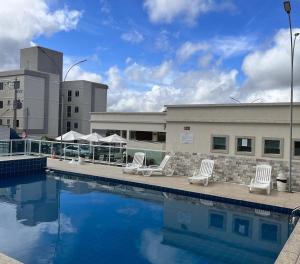 a swimming pool with white chairs next to a building at Apto ao lado do Shopping Caruaru próximo ao pátio unidade 302 in Caruaru