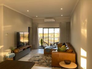 a living room with a bed and a television at Urban Awe Apartment: Sarona City in Gaborone