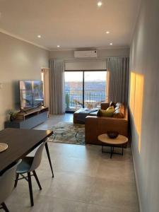 a living room with a couch and a television at Urban Awe Apartment: Sarona City in Gaborone
