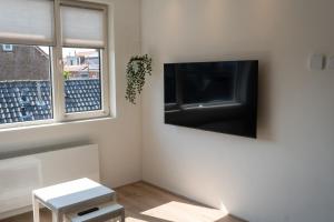 Una sala de estar con un televisor de pantalla plana en una pared. en Appartement aan Zee, en Noordwijk aan Zee