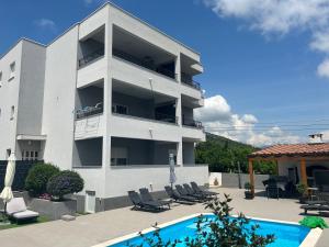 een wit appartementengebouw met een zwembad ervoor bij Villa Apartment AA 2 in Trogir