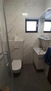 a white bathroom with a sink and a toilet at Holiday Home Family - 100m from sea in Vantačići