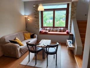 ein Wohnzimmer mit einem Sofa, einem Tisch und einem Fenster in der Unterkunft Chalet Mila in Mavrovo-Nationalpark