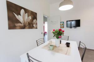ein Esszimmer mit einem weißen Tisch mit Blumen darauf in der Unterkunft Appartamento Torregalli, confortevole e moderno in Scandicci