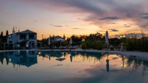 Sun 'n Chill, Boutique Apartments & Beach Villa في Melíkia: مسبح كبير مع غروب الشمس في الخلفية