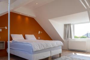 a bedroom with a bed with an orange wall at Appartement aan Zee in Noordwijk