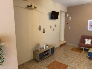 a living room with a couch and a tv on the wall at Hotel Manos in Paralia Katerinis