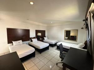 a hotel room with two beds and a desk at Hotel Don Quijote in Mexicali