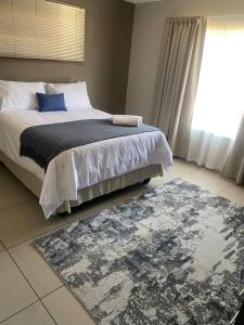 a bedroom with a bed and a rug and a window at Waterford Executive Apartments in Mbabane