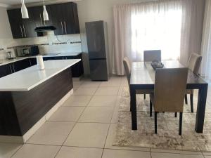 a kitchen with a table and chairs and a refrigerator at Waterford Executive Apartments in Mbabane