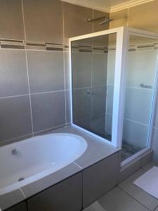 a bathroom with a tub and a glass shower at Waterford Executive Apartments in Mbabane +16 photos
