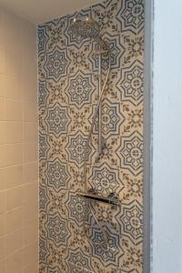 een douche in een badkamer met een betegelde muur bij Appartement aan Zee in Noordwijk