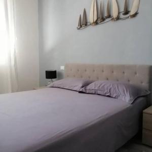 um quarto com uma grande cama branca com almofadas roxas em CasaConte Guesthouse em Viareggio