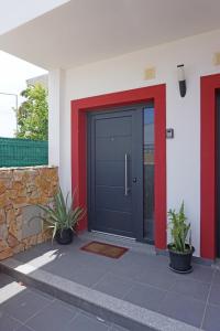 een zwarte voordeur van een huis met twee planten bij Casa Gaio's in Parchal