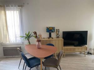 una mesa y sillas en una sala de estar con TV en Appartement cosy à Bordeaux, en Burdeos