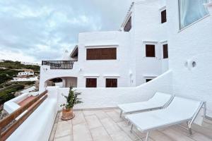 uma varanda branca com uma mesa e uma cadeira em Luxury House 80m2 Terrace em Cala Morell