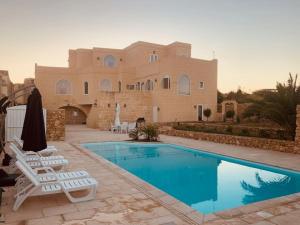 uma casa com piscina e duas espreguiçadeiras em Farmhouse Villa with Large Pool and Garden in Gozo em Għarb