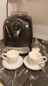 two cups and plates on a counter with a toaster at Romantic2 in Szeged