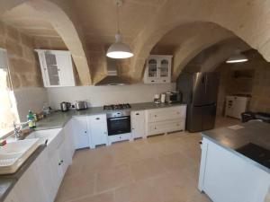 uma grande cozinha com armários brancos e um tecto de pedra em Farmhouse Villa with Large Pool and Garden in Gozo em Għarb