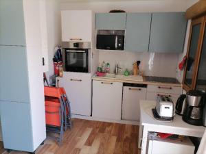 a kitchen with white cabinets and a white refrigerator at Océane in Gujan-Mestras