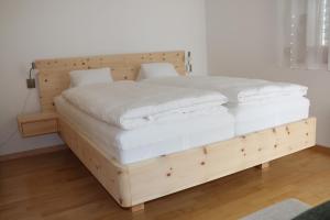 una cama de madera con sábanas blancas y almohadas. en Chasa Azura, en Scuol
