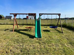 a playground with two swings and a slide at Domki Dafi in Jarosławiec