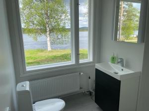 a bathroom with a toilet and a sink and a window at Napapiirin Eräkartano in Pello